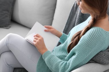 Evde kitap okuyan güzel genç bir kadın.