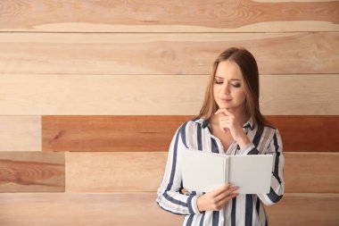 Kitap ahşap duvarının yakınında olan güzel kadın