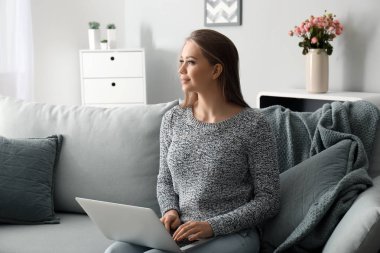 Evde dizüstü bilgisayarda çalışan genç bir kadın.