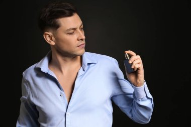 Yakışıklı adam koyu arka plan üzerinde parfüm şişe