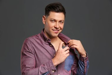 Yakışıklı adam gri arka plan üzerinde parfüm şişe