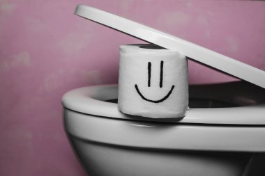 Rulo tuvalet tuvalet kase kapağı altında komik çizilmiş yüz ile kağıt paketler