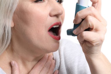 Beyaz arka plan üzerinde closeup saldırı astım inhaler ile olgun kadın