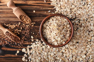 Yulaf gevreği, keten tohumu ve ahşap arka plan üzerinde buğday taneleri ile kase