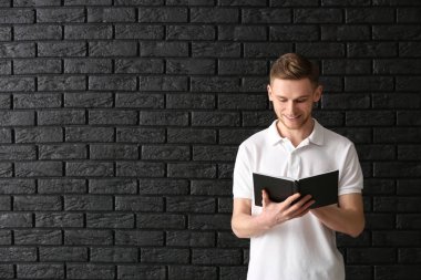 Yakışıklı delikanlı ile kitap karanlık duvara karşı