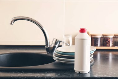 Temiz tabak ve deterjan evye yakınındaki şişe yığını