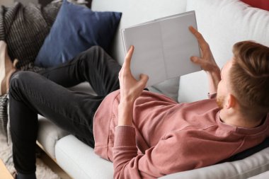 Evde kitap okuyan yakışıklı genç adam.