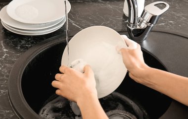 Mutfak lavabosunda bulaşık yıkayan kadın.
