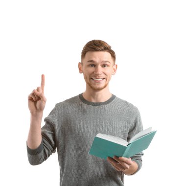 Kitap ve beyaz arka plan üzerinde yükseltilmiş işaret parmağı ile yakışıklı genç