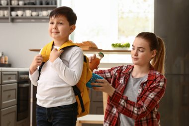 Anne koyarak öğle yemeği kutusu içine küçük oğlu okul öncesi ve sırt çantası