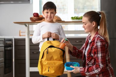 Anne koyarak öğle yemeği kutusu içine küçük oğlu okul öncesi ve sırt çantası