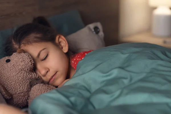 自宅のベッドにテディベアとかわいい眠っている女の子 — ストック写真