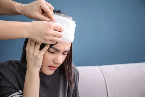 Woman applying bandage onto female head