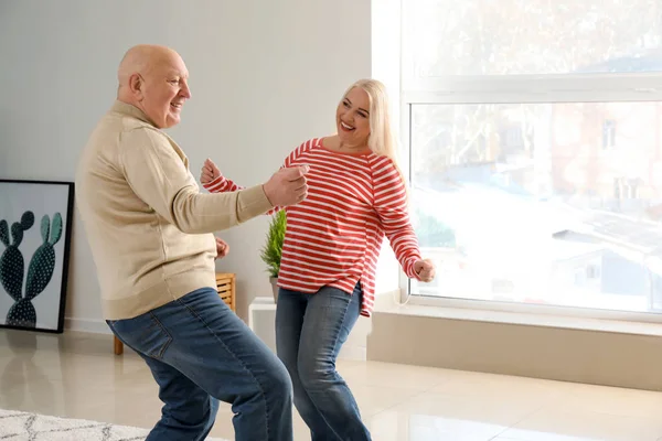 Cute elderly couple dancing at home