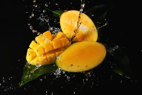 Ripe cut mango with water splash on dark background