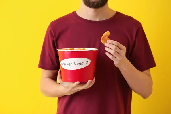 Schöner Mann Mit Einem Eimer Leckerer Nuggets Auf Farbigem Hintergrund — Stockfoto