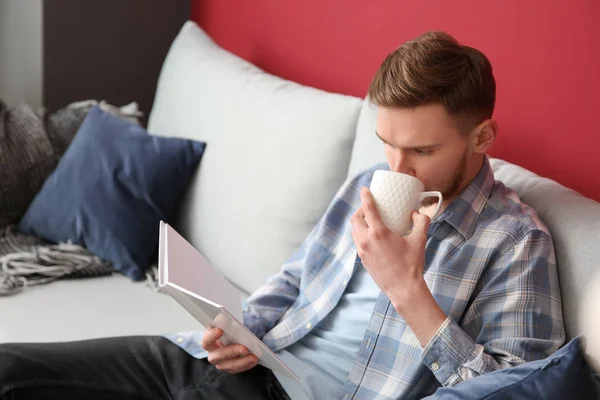 Jonge Man Drinken Koffie Terwijl Het Lezen Van Boek Thuis — Stockfoto