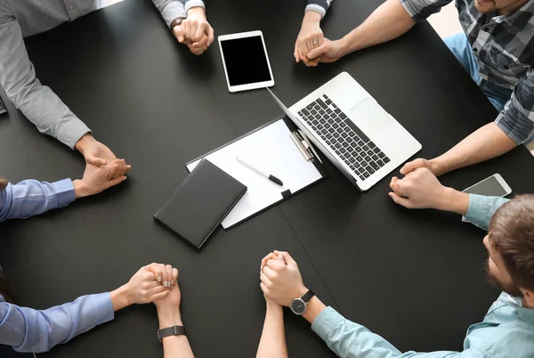 Group of people praying before meeting in office