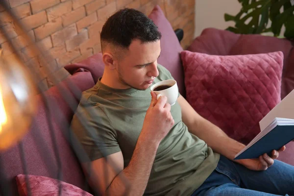 Mladý Muž Pití Kávy Při Čtení Knihy Doma — Stock fotografie
