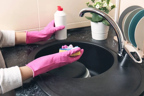 Woman washing dishware in kitchen