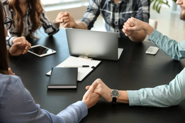 Group of people praying before meeting in office