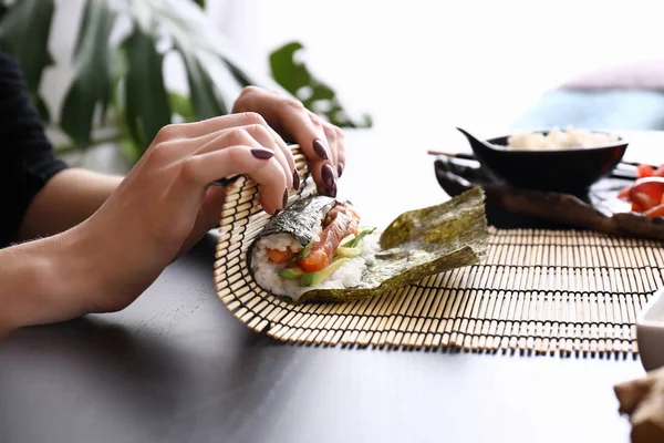 テーブルでおいしい寿司ロールを作る女性 — ストック写真