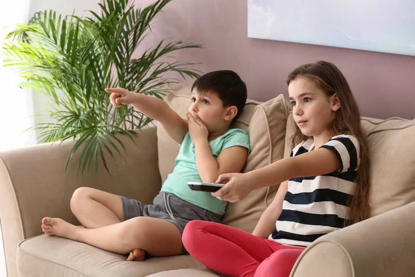 Emotional little children watching cartoons on TV at home