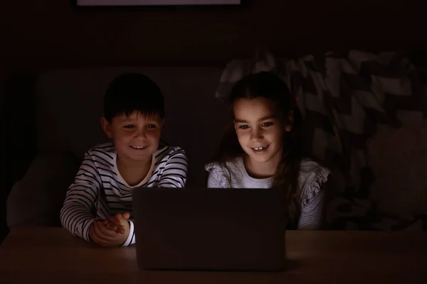 Cute little children with laptop watching cartoons late in evening