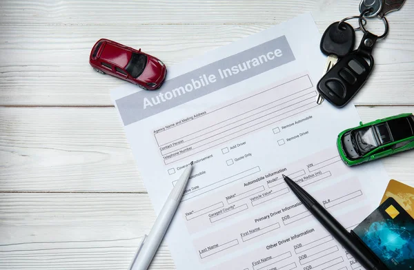 Automobile insurance form with car keys on white table