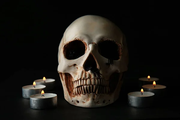 人的头骨和燃烧的蜡烛在黑色背景 — 图库照片