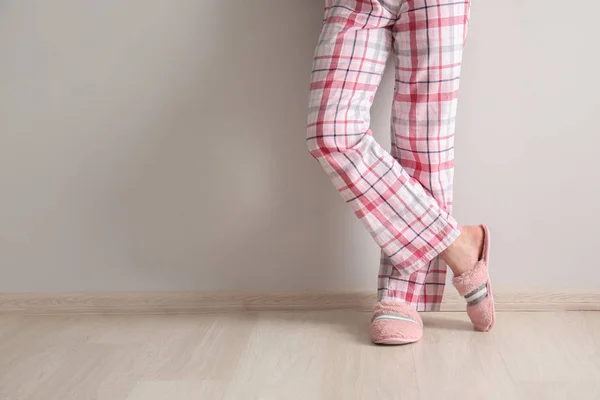 Young woman in slippers near white wall