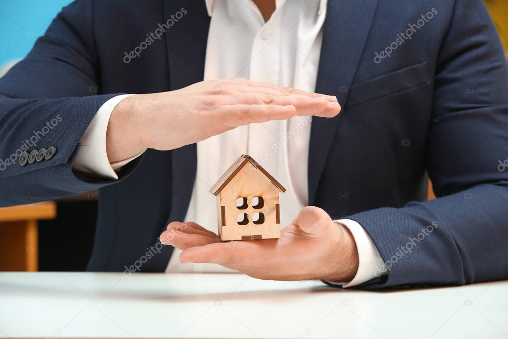 Insurance agent holding figure of house, closeup