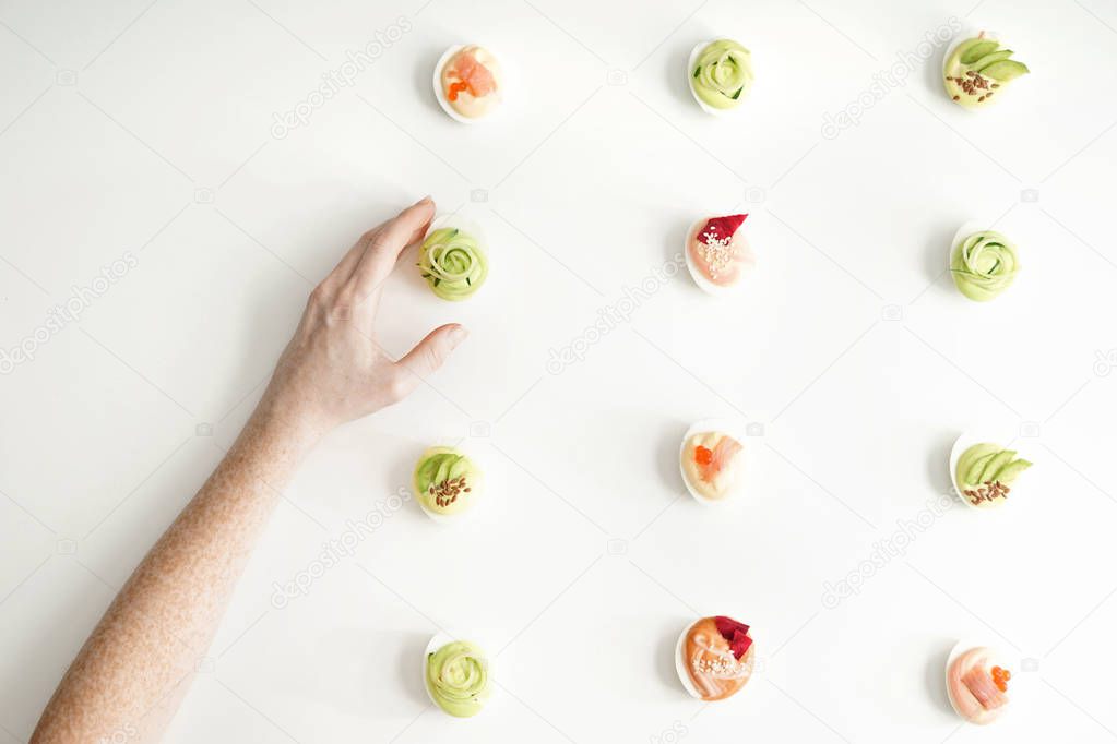 Female hand and tasty deviled eggs on white background