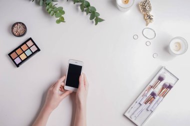 Güzellik blogger ile cep telefonu ve beyaz arka plan üzerinde makyaj kozmetik