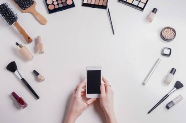 Güzellik blogger ile cep telefonu ve beyaz arka plan üzerinde makyaj kozmetik