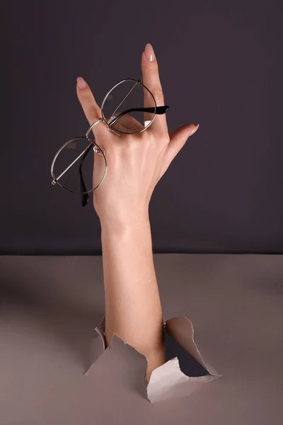 Female Hand Holding Stylish Eyeglasses Hole Torn Paper — Stock Photo, Image
