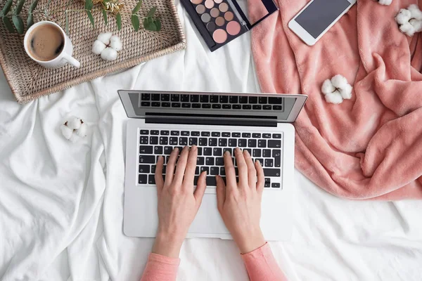Beauty blogger working with laptop on bed
