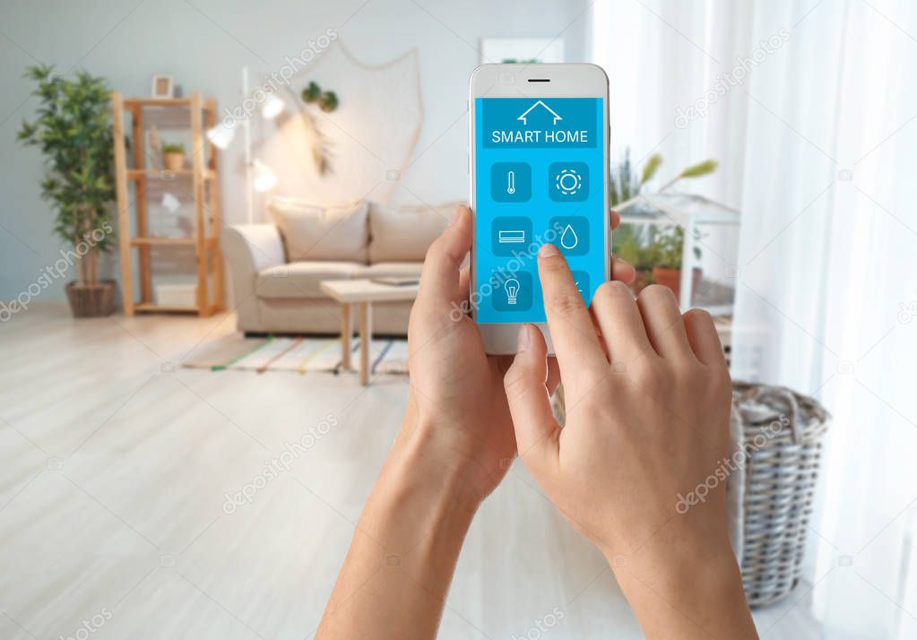 Woman using mobile phone application of smart home automation in room