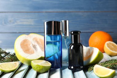 Şişe parfüm, narenciye meyve ve çam dalları masada