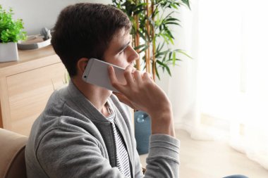 Evde cep telefonu üzerinde konuşurken yakışıklı genç