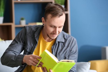 Evde kitap okuyan yakışıklı genç adam.