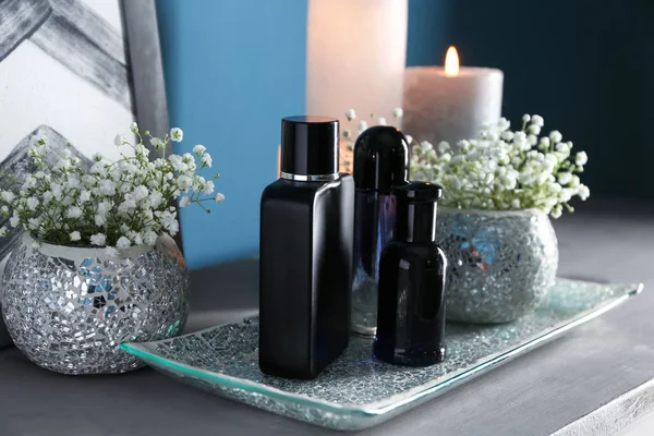 Bottles of perfume, flowers and candles on table