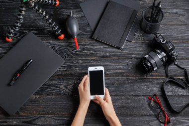Kadın fotoğrafçı ile cep telefonu işyerinde, üstten görünüm