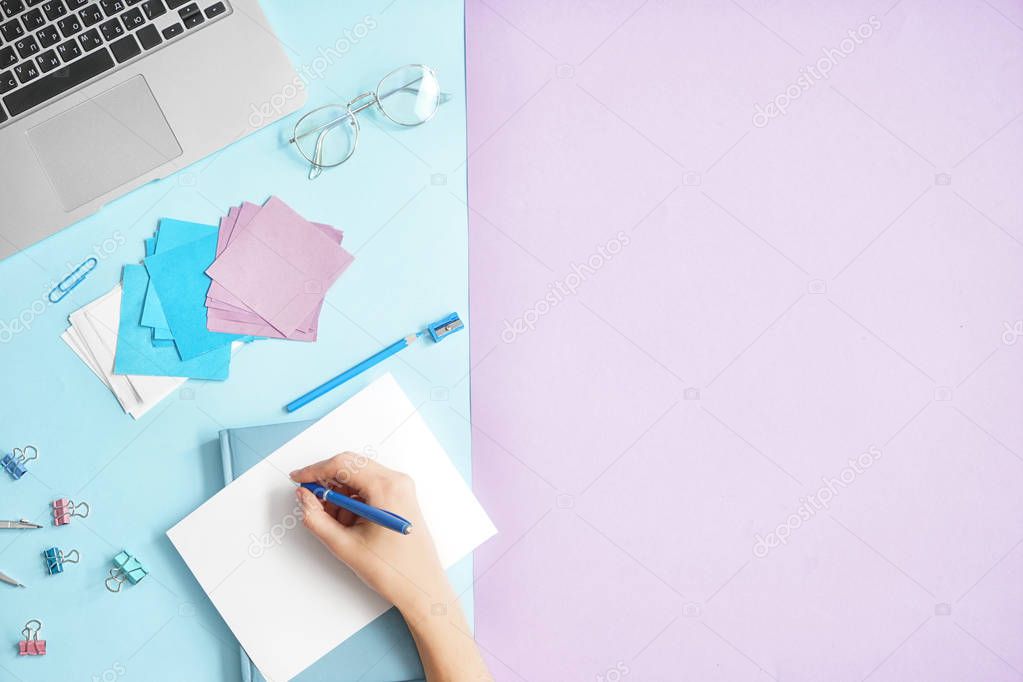 Woman writing in notebook on color background, top view