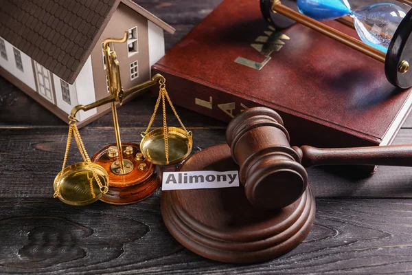 Judge\'s gavel, scales of justice, house model and paper with text ALIMONY on table