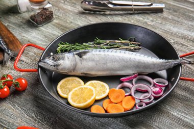 Ahşap masa üzerinde lezzetli çiğ uskumru balığı ile kızartma tavası