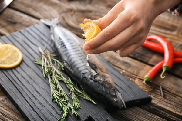 Kadın lezzetli uskumru balığı, closeup üzerine limon suyu sıkma