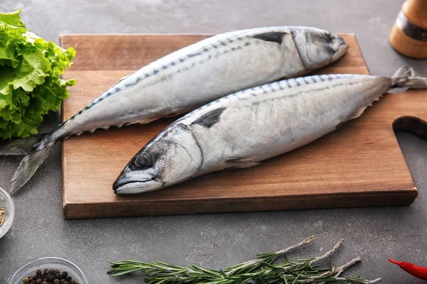 Ahşap tahta ile gri masada lezzetli çiğ uskumru balığı