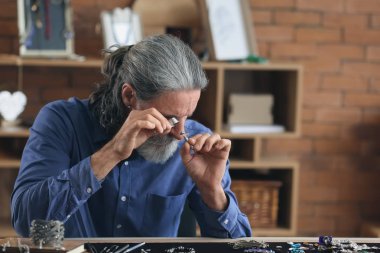 Mücevher atölyesinde mücevher inceliyor.