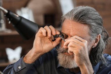 Mücevher atölyesinde mücevher inceliyor.